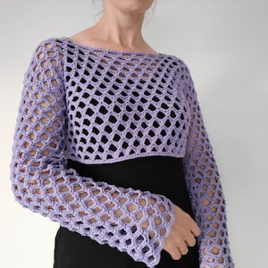 May include: A lavender crochet top with a loose, open-weave design. The top has long sleeves and a cropped length.