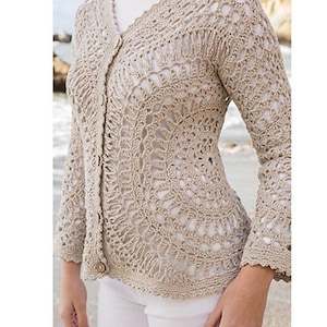 Puede incluir: Cárdigan de crochet beige de tejido abierto con mangas largas y cierre de botones. El cárdigan presenta un delicado patrón de encaje y un escote en V. Las mangas tienen un ligero ensanchamiento en la muñeca.