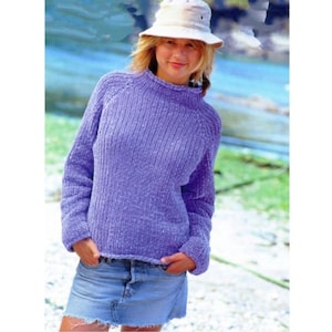 Può includere: Un maglione di lana color lavanda con collo alto e maniche lunghe. Il maglione è realizzato con un filato morbido e testurizzato.