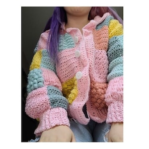 May include: A pink, green, yellow and orange crochet cardigan with a button fastening. The cardigan is made from a soft, textured yarn and has a patchwork design.