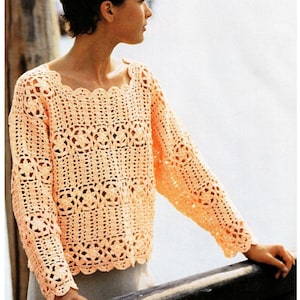 May include: A crocheted top with a delicate, lacy pattern in a light peach color. The top has long sleeves and a scoop neckline.