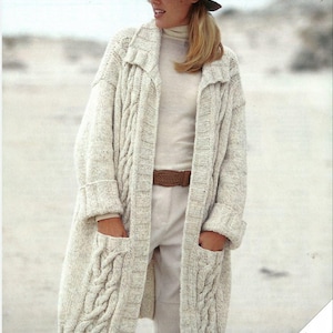 Puede incluir: Un cárdigan blanco de punto de cable con bolsillos y cuello. El cárdigan es largo y tiene un corte holgado. La modelo lleva un jersey de cuello alto blanco y un cinturón marrón. La imagen incluye el texto "DENIM Chunky" y "Sirdar".