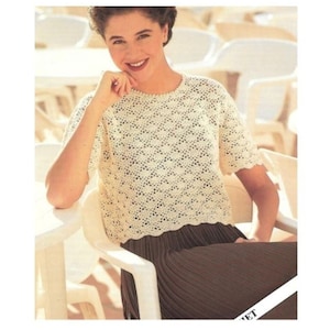 May include: A white crocheted top with a scalloped hem. The top has a round neckline and short sleeves.