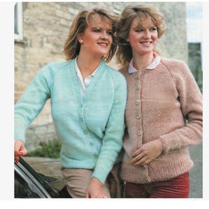Może przedstawiać: Dwie kobiety w dzianinowych kardiganach. Kobieta po lewej stronie nosi jasnoniebieski kardigan zapinany na guziki. Kobieta po prawej stronie nosi jasnoróżowy kardigan zapinany na guziki.