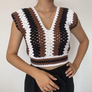 May include: A white, brown and black striped crochet top with a v-neck and short sleeves.