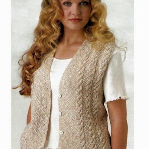 May include: A beige knitted waistcoat with a cable knit pattern and button fastening. The waistcoat has a V-neck and a slightly longer back than front.