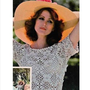 Puede incluir: Una mujer con un top blanco de crochet, un sombrero de paja de ala ancha y una flor rosa. El top tiene un delicado patrón floral y mangas cortas.