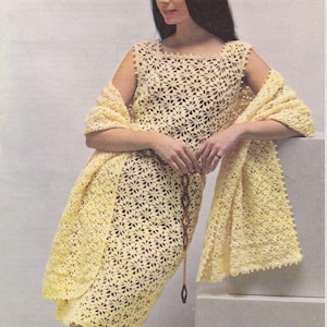 Könnte beinhalten: Ein gelbes Häkelkleid und ein passender Schal mit Blumenmuster. Das Kleid ist ärmellos und hat einen runden Ausschnitt. Der Schal ist über die Schultern gelegt und hat einen Fransenrand.