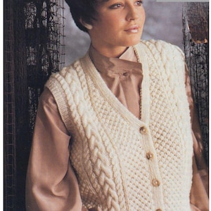 Op de afbeelding: Een wit gebreid vest met een kabelbreipatroon en knoopsluiting. Het vest is gemaakt van Aran/Worsted garen en is 30-40 inch lang.