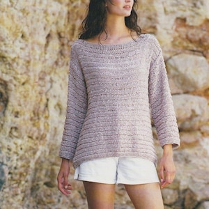 May include: A light pink knitted jumper with a loose fit and long sleeves. The jumper is made with a ribbon yarn and has a boat neck. The text "Celeste Ribbon Yarn 32 - 42 ins" is visible on the image.