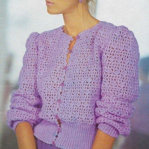 May include: A crocheted cardigan in a light purple color with a button-up front and long sleeves. The cardigan has a delicate openwork pattern and a fitted silhouette.