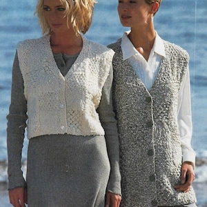 May include: Two women wearing knitted vests. The woman on the left is wearing a white vest with a delicate pattern and a grey skirt. The woman on the right is wearing a grey vest with a textured pattern and grey trousers.