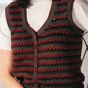 Könnte beinhalten: Eine braune und grüne gehäkelte Weste mit Knopfleiste. Die Weste hat ein gestreiftes Muster mit einer welligen Textur.