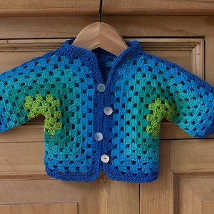 May include: A blue and green crocheted cardigan with a button closure. The cardigan has a gradient pattern of blue and green squares.
