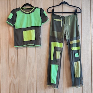 Puede incluir: Una camiseta de malla verde con un panel de malla negra y un pantalón de malla verde con paneles de malla negra.