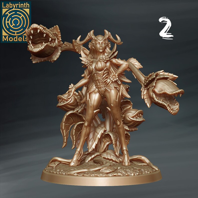 May include: A gold-colored miniature figurine of a female figure with antlers, standing on a base with plant-like features. The figure is wearing a leafy outfit and holding a plant with a large, open mouth.