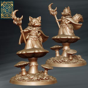 May include: Two golden painted figurines of fox-like creatures with wings and holding staffs. They are standing on mushroom-shaped bases with smaller mushrooms surrounding them.