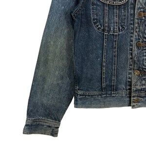 Puede incluir: Una chaqueta vaquera azul con cierre de botones y mangas largas. La chaqueta tiene un aspecto descolorido y est&aacute; hecha de un material suave y c&oacute;modo.