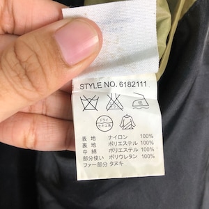 Puede incluir: Una etiqueta blanca con texto negro y s&iacute;mbolos. La etiqueta tiene un n&uacute;mero de estilo, "STYLE NO. 6182111", y detalla la composici&oacute;n del tejido de la prenda. El tejido est&aacute; hecho de nylon, poli&eacute;ster y poliuretano. La etiqueta tambi&eacute;n incluye instrucciones de cuidado, incluyendo un s&iacute;mbolo para la limpieza en seco y un s&iacute;mbolo para planchar a baja temperatura.