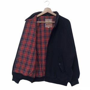 May include: A dark navy blue jacket with a full-length front zipper and a fold-down collar. The interior is lined with a red, green, and blue plaid fabric. A rectangular brand label is stitched at the inner neckline featuring the text "LOGG".