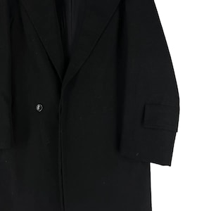 May include: A black overcoat with a single-button closure and a notched lapel. The coat features a tailored fit and a small pocket on the sleeve. The fabric appears to be a smooth, solid material.
