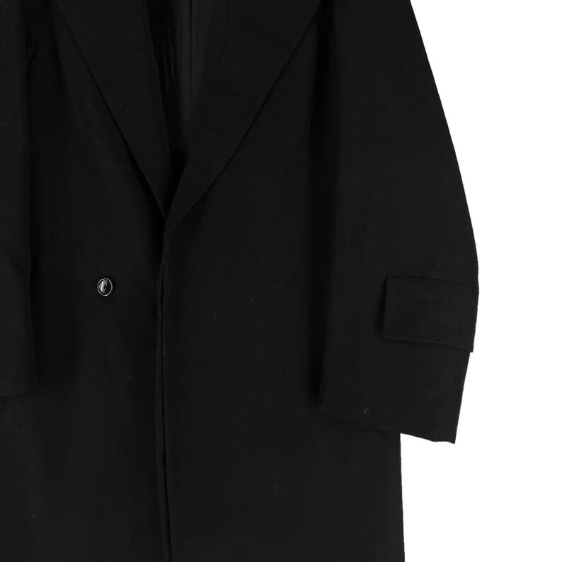 May include: A black overcoat with a single-button closure and a notched lapel. The coat features a tailored fit and a small pocket on the sleeve. The fabric appears to be a smooth, solid material.