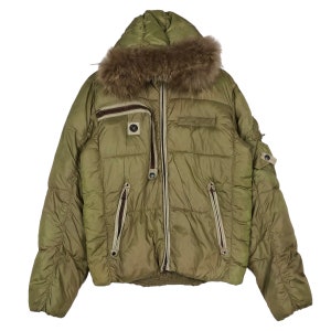 Puede incluir: Una chaqueta acolchada verde con capucha forrada de piel. La chaqueta tiene cierre de cremallera y varios bolsillos.