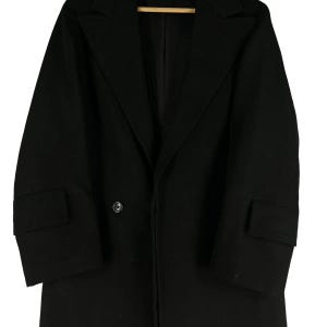 May include: A black double-breasted coat with a notched lapel and two front pockets. The coat has a single button closure and a classic, tailored design. The coat is made of a solid black fabric.