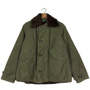 May include: Olive green military-style jacket with a brown faux fur collar. The jacket features a button-up front, two front pockets, and buttoned cuffs. The jacket is hanging on a wooden hanger.