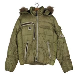 Puede incluir: Una chaqueta acolchada verde con capucha forrada de piel y varios bolsillos con cremallera.