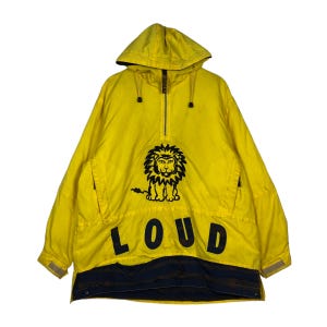 May include: Yellow hooded anorak with a black lion graphic and the word "LOUD" in bold letters. The anorak has a half-zip closure, front pockets, and a dark blue band at the bottom. The jacket is a vintage style.