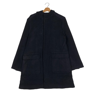 May include: A dark navy blue coat with a high collar and two large front pockets. The coat is hanging on a wooden hanger against a white background. The coat's design is simple and classic.