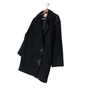 May include: A black wool coat with a double-breasted design, hanging on a wooden hanger. The coat features leather accents on the shoulders and decorative closures. The coat is a classic outerwear piece.