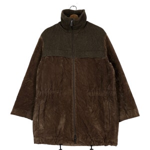 May include: A brown jacket featuring a high ribbed collar and a full-length front zipper. The upper chest area is constructed from a textured knit fabric, while the lower body is made of a smooth, slightly wrinkled material with two side pockets.