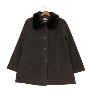 May include: A dark brown coat with a black faux fur collar. The coat has a button-up front, two front pockets, and a classic design. The coat is hanging on a wooden hanger.