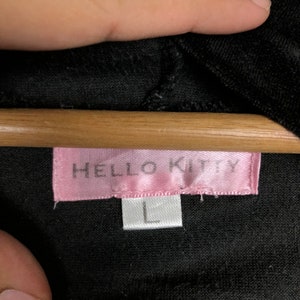 May include: A black Hello Kitty shirt with a pink Hello Kitty label and a white size label that says "L".