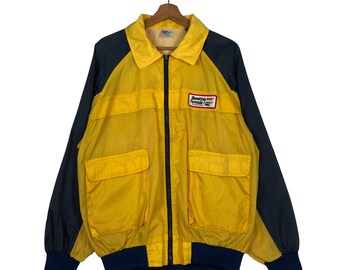 May include: Yellow and navy blue vintage jacket with a zip-up front, two front pockets, and a Benetton Formula logo patch. The jacket has a collared neckline and elastic cuffs and hem.