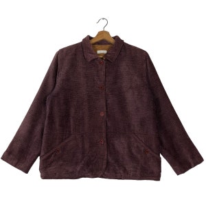 May include: A burgundy button-down jacket with a textured fabric. The jacket has a collar, two front pockets, and is hanging on a wooden hanger. The jacket has four buttons down the front.