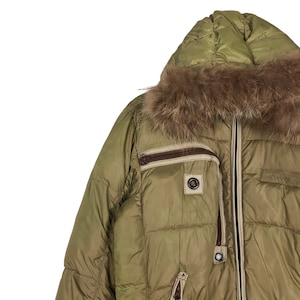 Puede incluir: Una chaqueta acolchada verde con capucha forrada de piel marr&oacute;n. La chaqueta tiene cierre de cremallera y varios bolsillos.