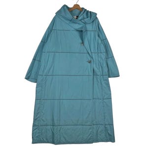 May include: A long, light blue coat with a hood and a unique wrap-around design. The coat features horizontal stitching and two buttons. The coat is hanging on a wooden hanger.