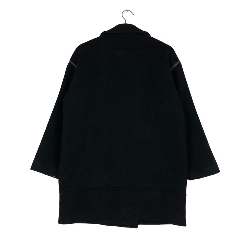 May include: A black wool coat with a classic design, hanging on a metal hanger. The coat features a wide collar, long sleeves, and a mid-thigh length. The coat is a solid black color.