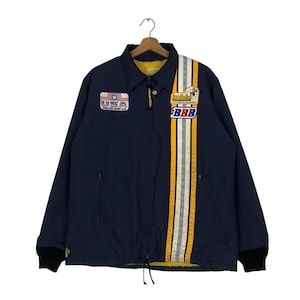 May include: A navy blue jacket with a yellow, white, and gray stripe down the center. The jacket has a zipper closure and two pockets. The jacket has patches with the text "HRSA" and "Dumbledeer" on the front.