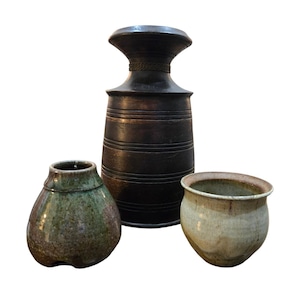 May include: Three ceramic vases of varying shapes and colors. The tallest is dark brown with horizontal lines and a flared top. A smaller, rounded vase is green and brown. The third is a light beige, open-mouthed pot.