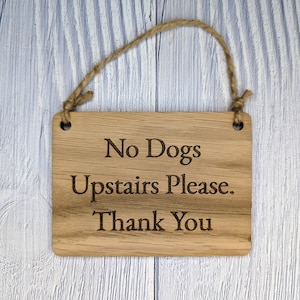 May include: A wooden sign with a rope hanger that reads "No Dogs Upstairs Please. Thank You".