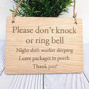 May include: A wooden sign with the text "Please don't knock or ring bell. Night shift worker sleeping. Leave packages in porch. Thank you!"
