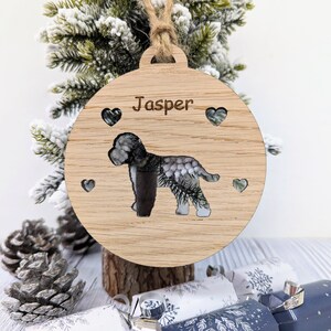 May include: A wooden Christmas ornament with a cutout of a dog and the name "Jasper" engraved on it. The ornament is decorated with small hearts.