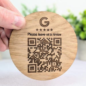 May include: A round wooden coaster with a laser-etched design. The coaster features the Google logo, five stars, a QR code, and the text "Please leave us a review."
