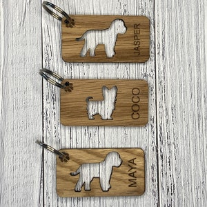 May include: Three wooden keyrings with dog silhouettes and names "Jasper", "Coco", and "Maya" engraved on them.