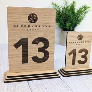 May include: Two wooden table number signs with a black base and the text "Cherrygrove Craft" and the number "13" on each sign.