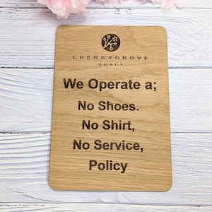 May include: Wooden sign with the text "CHERRYGROVE CRAFT" and the text "We Operate a; No Shoes. No Shirt, No Service, Policy".